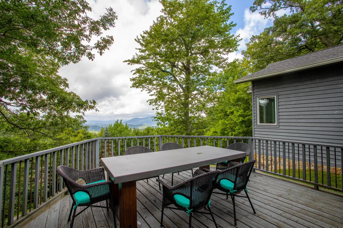 This image captures a large outdoor table surrounded by trees, with a stunning mountain view in the background. The setting is perfect for al fresco dining and group gatherings amidst nature, evoking a sense of celebration and togetherness in the great outdoors.