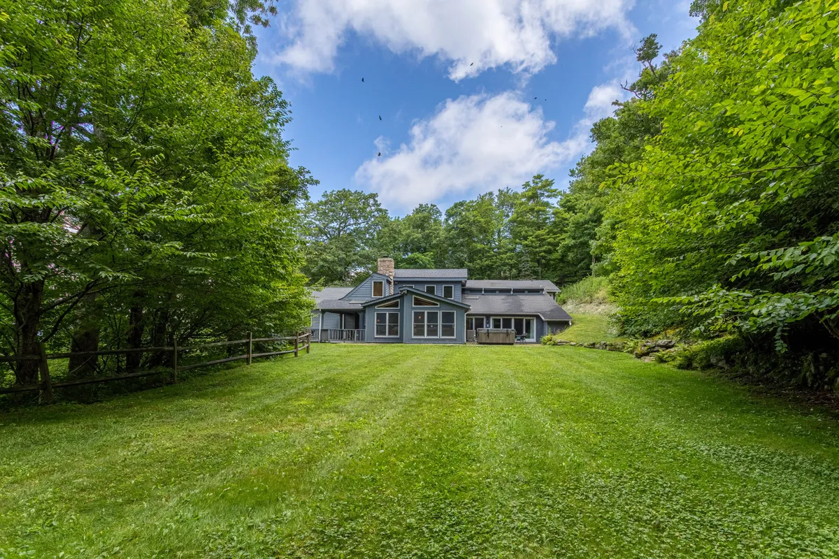 This photo captures the exterior of the home with a spacious lawn, mature trees, and the inviting facade. It offers a sense of seclusion and tranquility while illustrating the scale and private setting of the property.
