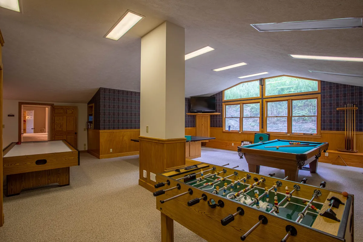 Featuring both a foosball table and a pool table, this image highlights a different angle of the rec room. Large windows provide plenty of natural light, and there’s a sense of relaxed fun ideal for group entertainment.